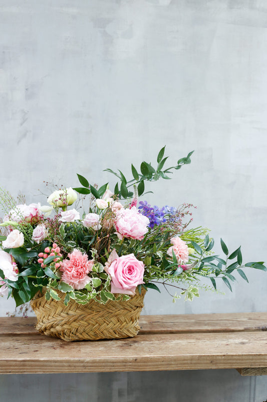 Flores de temporada en cesta de esparto