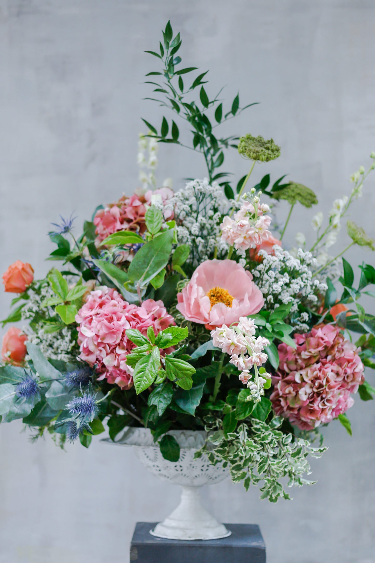 Arreglo de flores de temporada en copa blanca calada