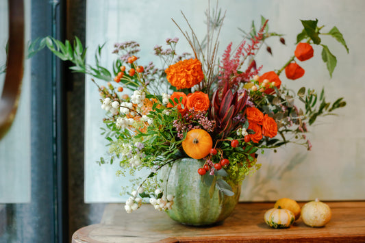 Arreglo de flores otoñal en jarrón aqua