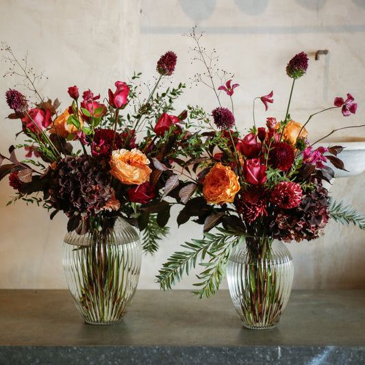 Flores otoñales burdeos en jarrón acanalado