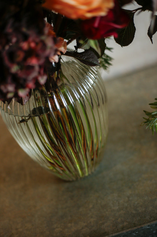 Flores otoñales burdeos en jarrón acanalado