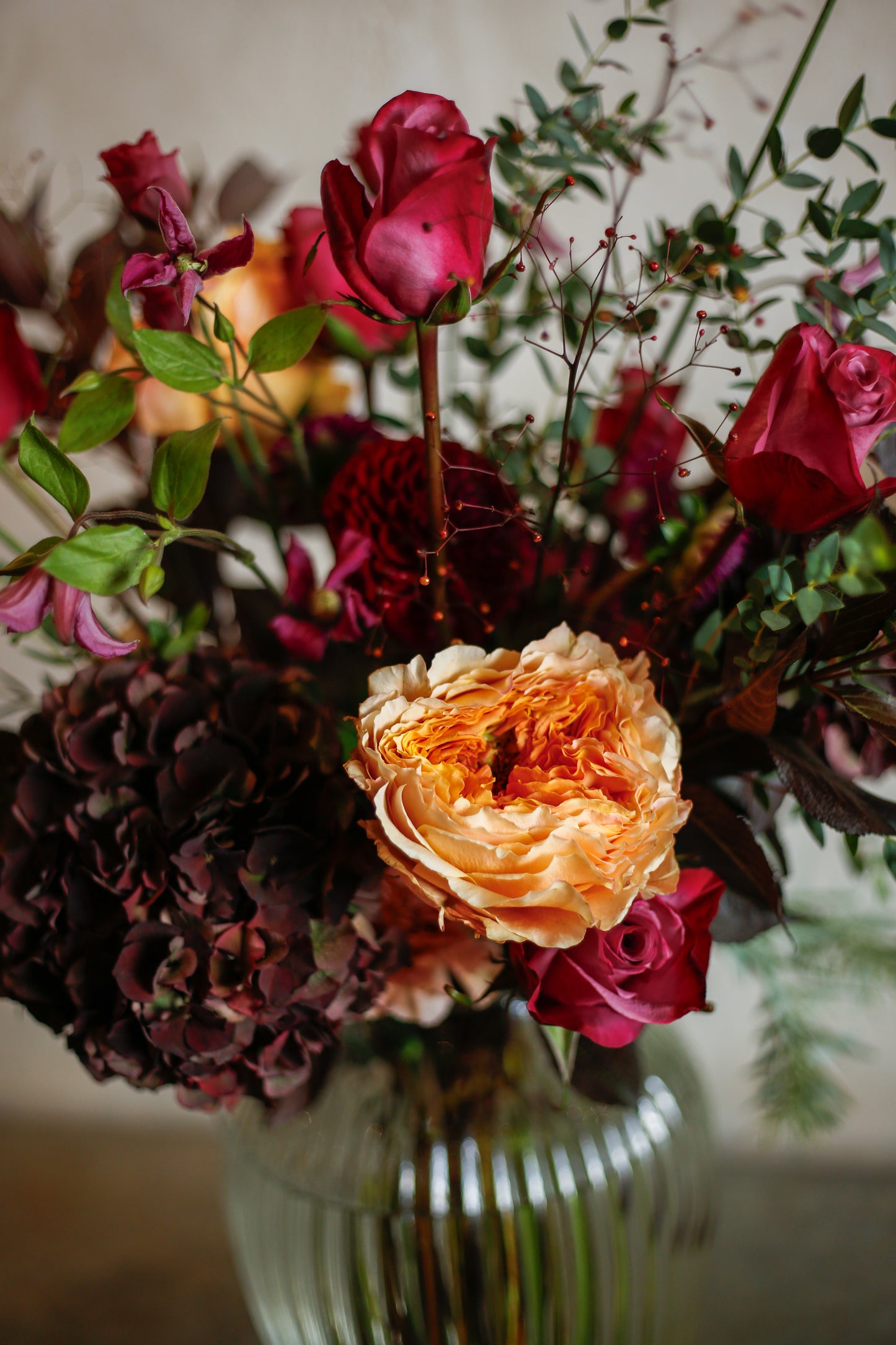 Flores otoñales burdeos en jarrón acanalado