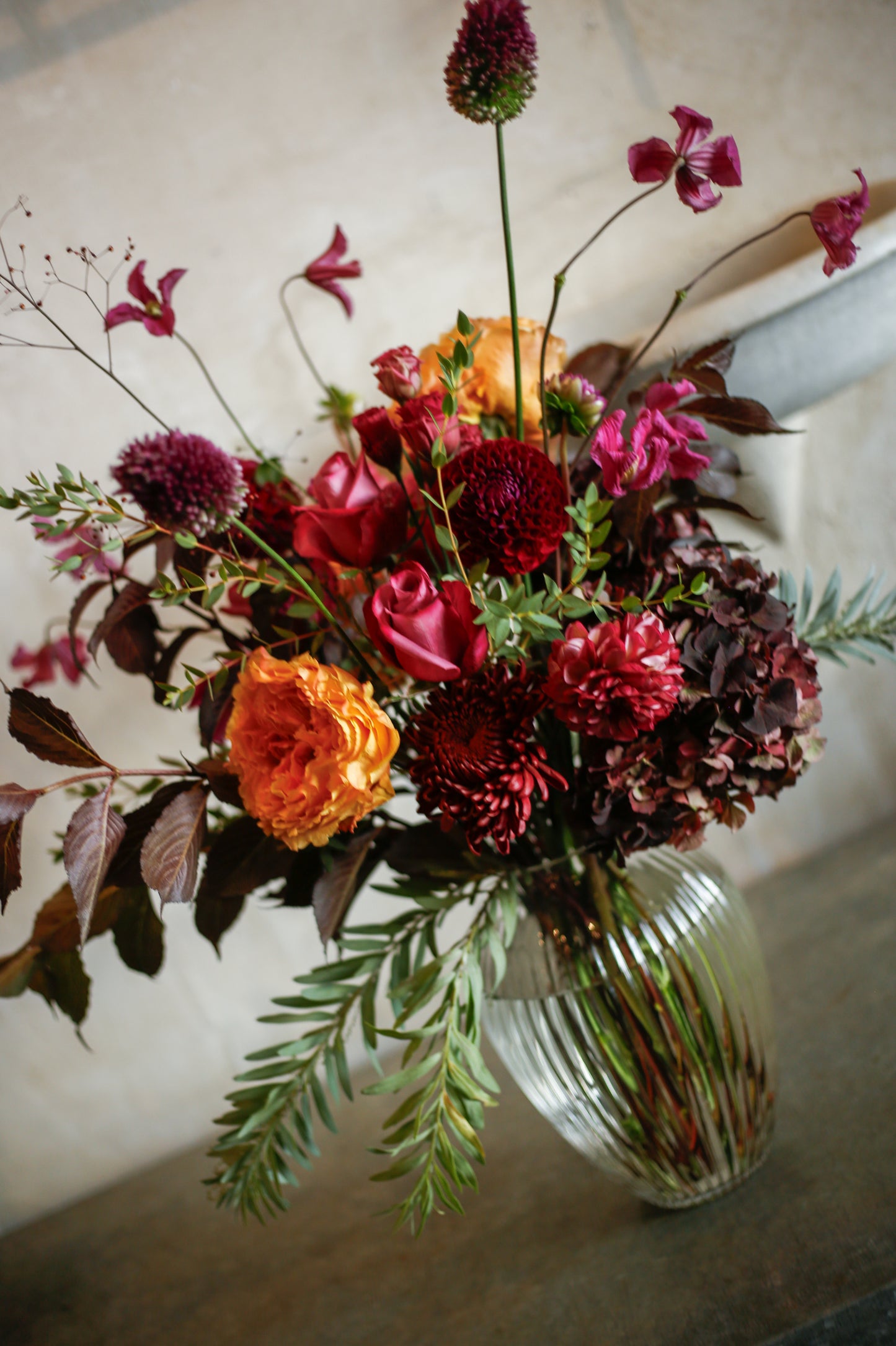Flores otoñales burdeos en jarrón acanalado